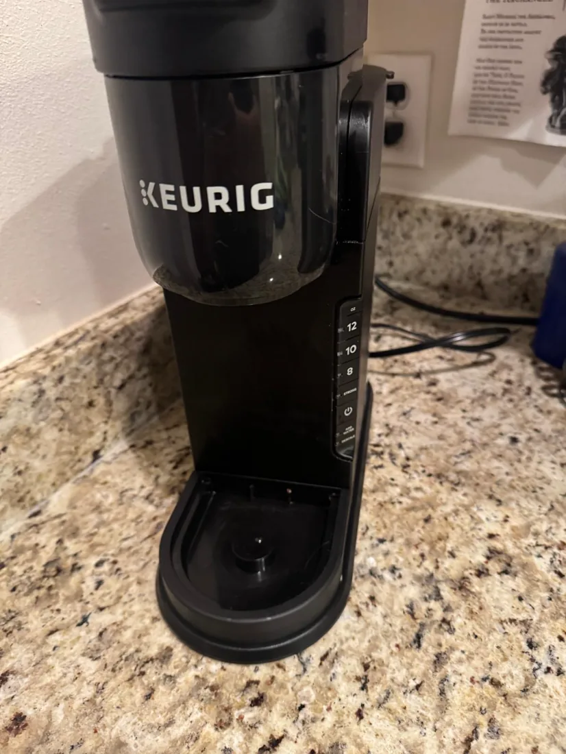 The same coffee maker wiped clean with a spotless drip tray after cleaning
